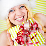 beautiful blonde woman holding a christmas gift is smiling