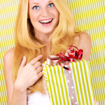 beautiful blonde woman holding a christmas gift is smiling